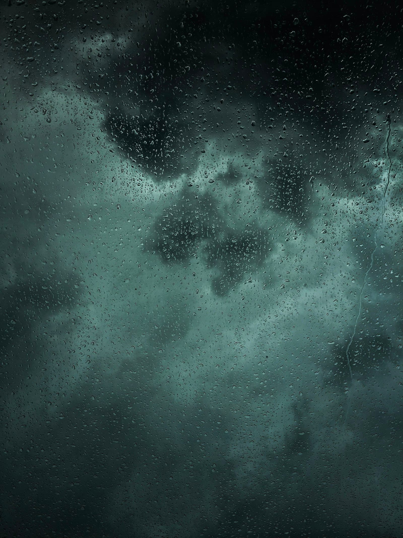 Raindrops on glass against a dark storm sky
